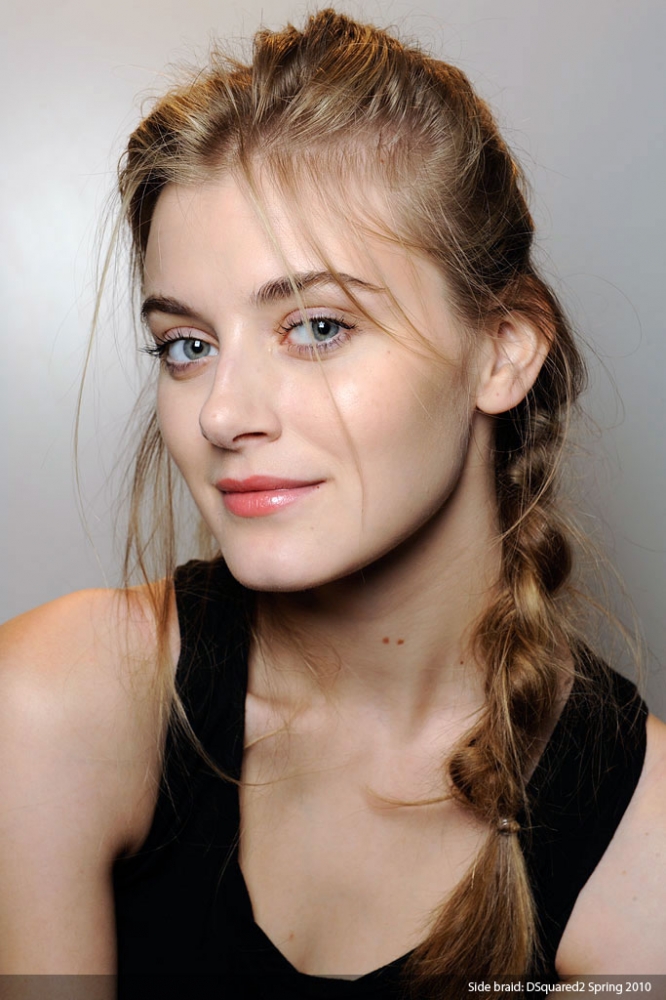 A young woman wearing a black top and braided hair.