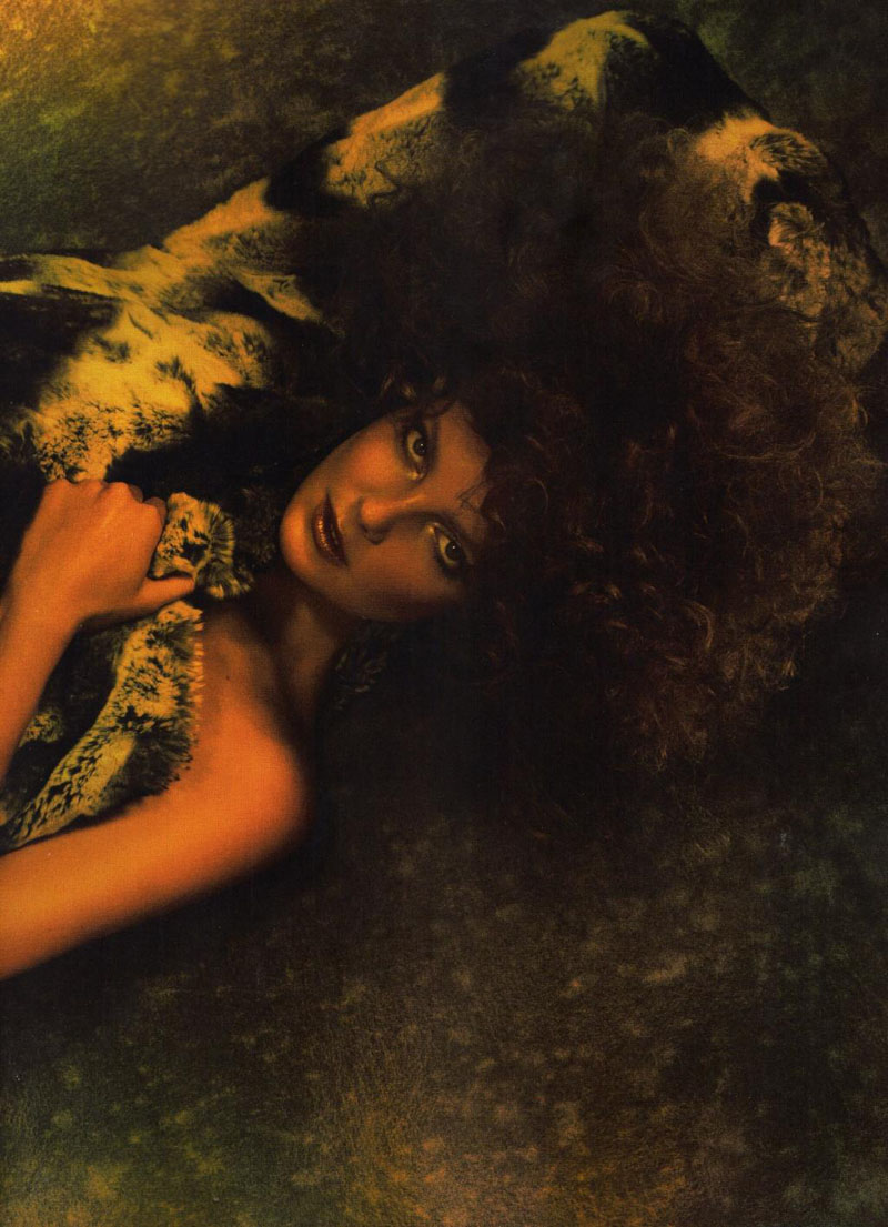 A woman with curly hair laying on the ground.