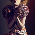 A woman in a floral dress posing on a bed.