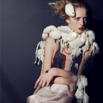 A woman sitting on a chair with feathers around her neck.