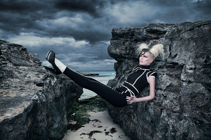 A woman is posing on a rocky cliff.