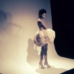 A woman in a white dress posing in a studio.