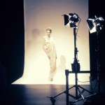 A woman in a dress is being photographed in a studio.