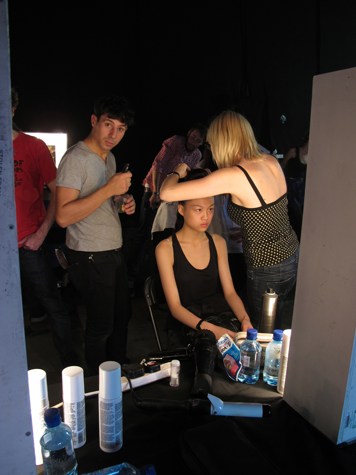 A group of people getting their hair done in front of a mirror.