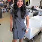 A woman in a gray dress posing in a salon.