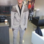 A young man in a gray suit standing in a salon.