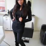 A woman in a black dress posing in a salon.