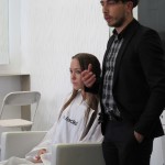 A man is standing next to a woman in a hair salon.