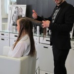 A man is cutting a woman's hair in a salon.