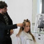 A man is cutting a woman's hair in a salon.