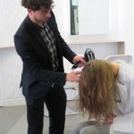 A man is blow drying a woman's hair.