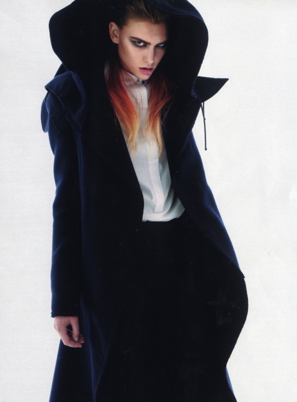 A woman in a black coat with red hair.