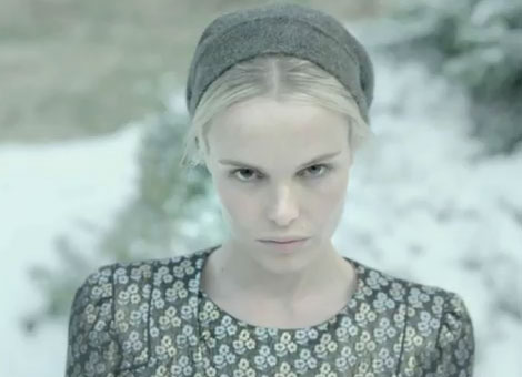 A woman in a black dress standing in the snow.