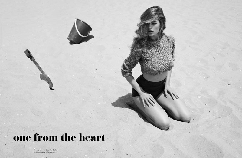 A woman sitting on the sand with a shovel in her hand.