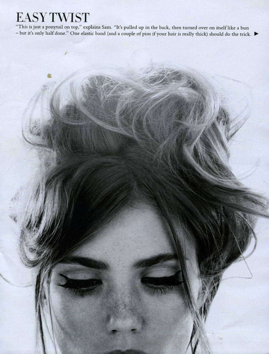 A black and white photo of a woman with her hair in a ponytail.