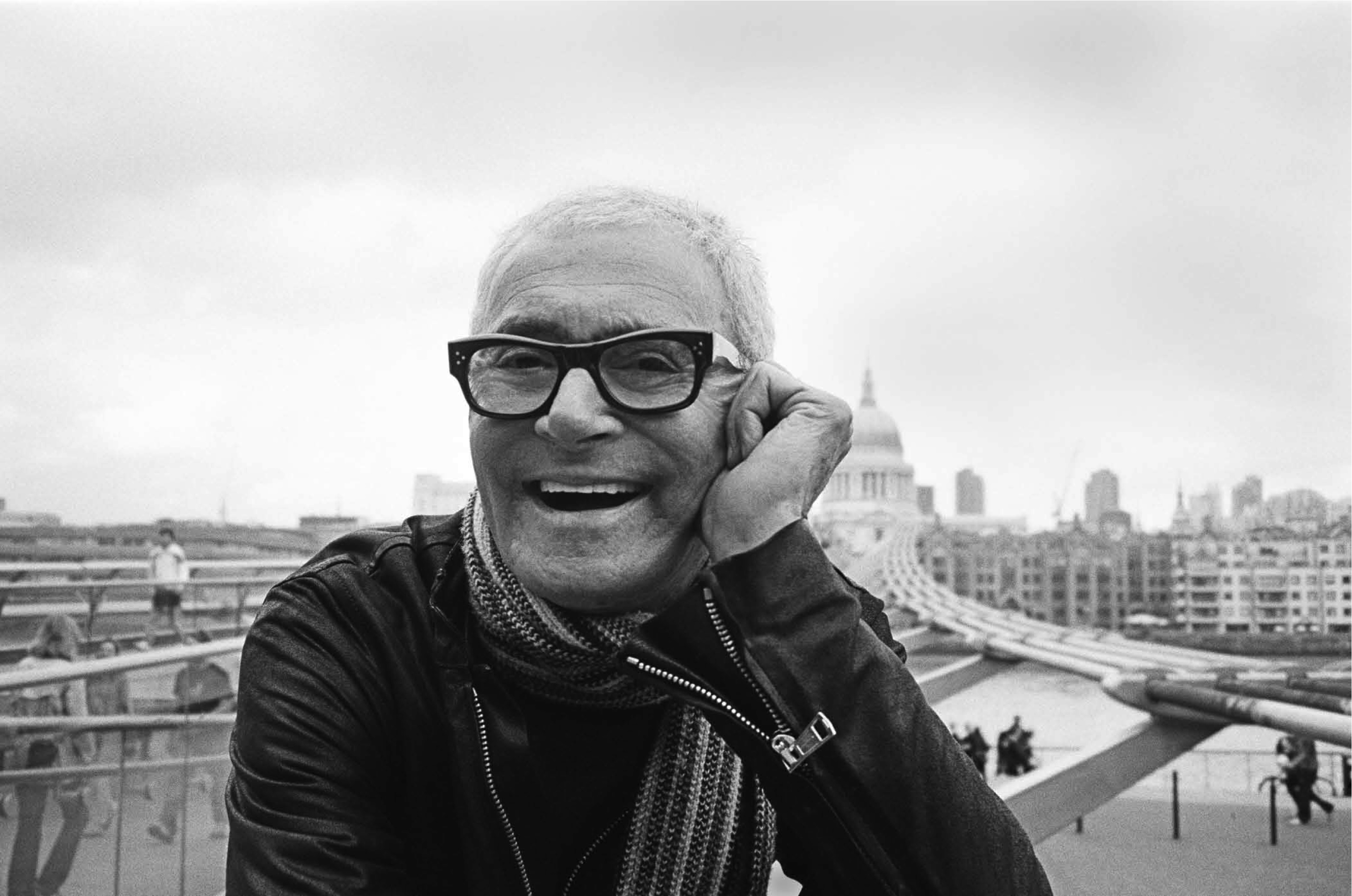 A black and white photo of a man with glasses and a scarf.