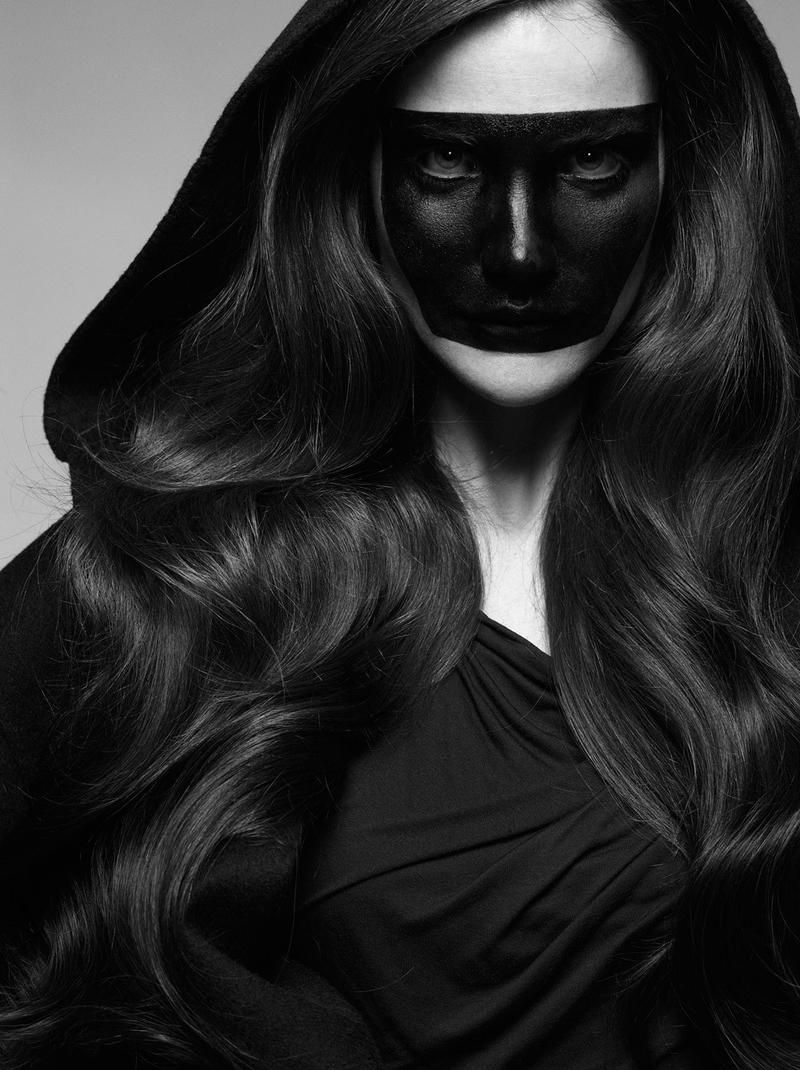 A black and white photo of a woman with a black mask on her face.