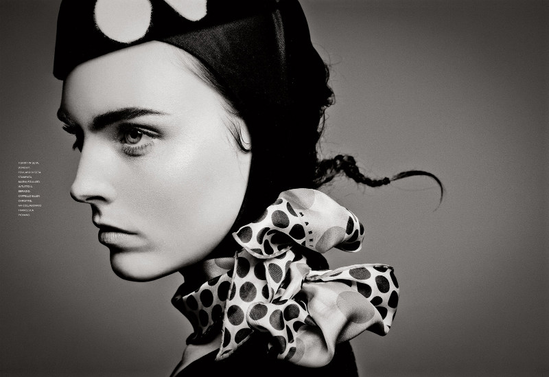 A black and white photo of a woman wearing a polka dot hat.