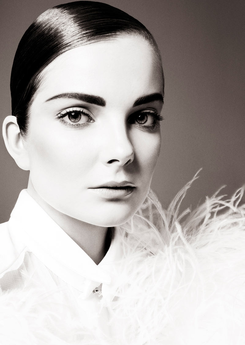 A black and white photo of a woman with feathers.