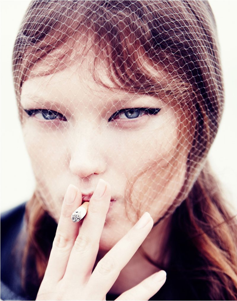 A woman wearing a hat smoking a cigarette.