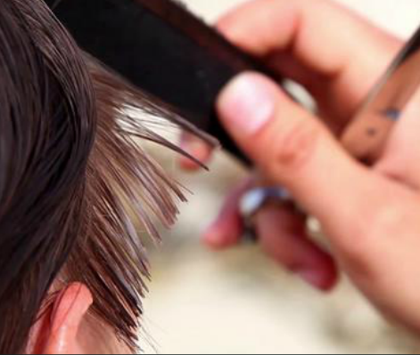 A woman is getting her hair cut by a hairdresser.