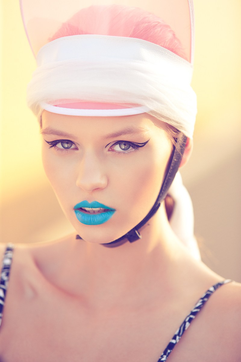 A woman wearing a pink hat and blue lipstick.