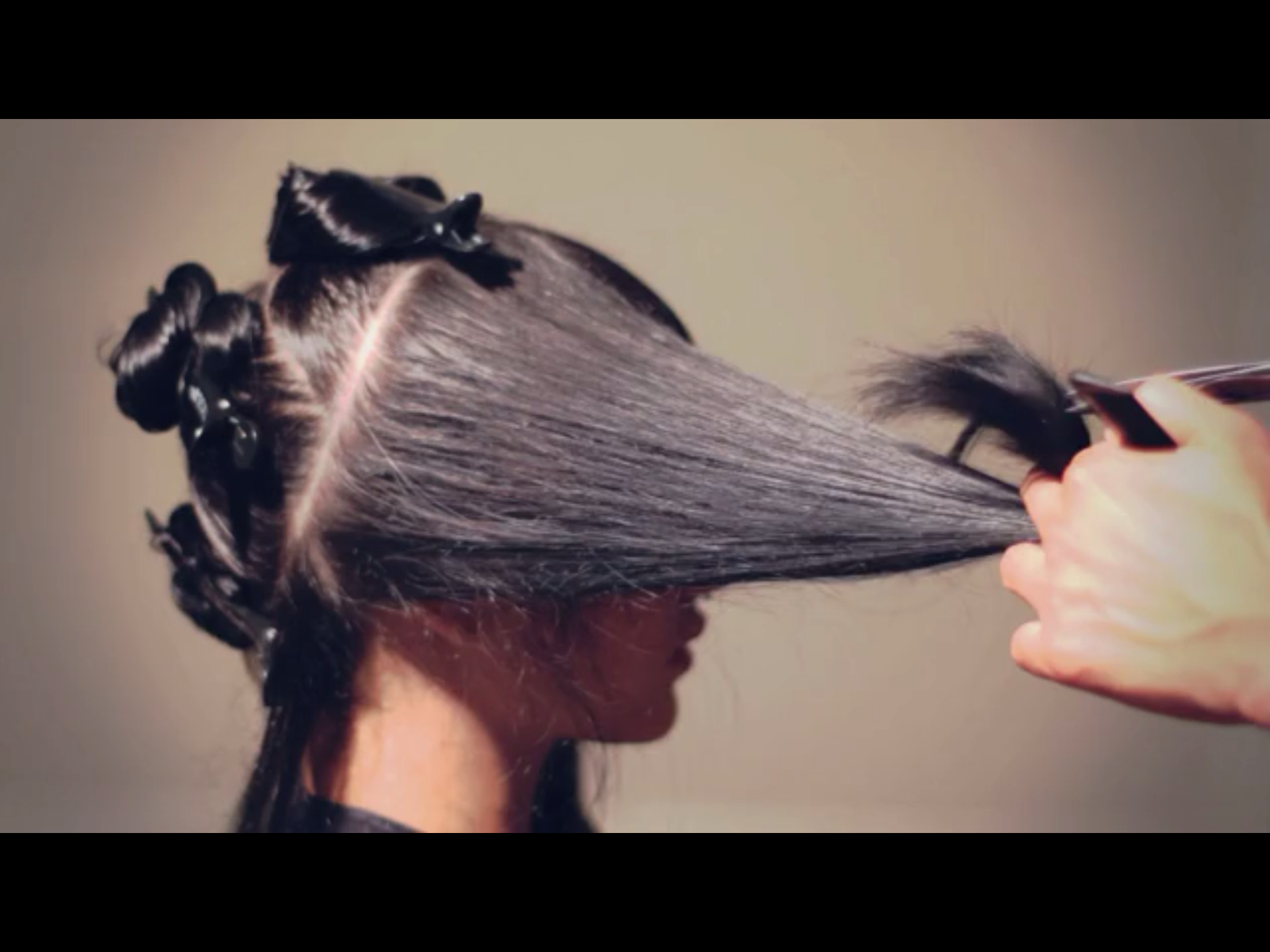 A woman is getting her hair braided by a hairdresser.