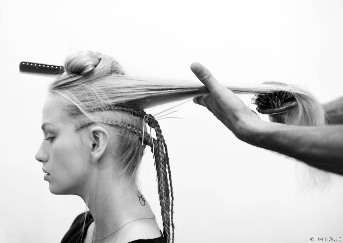 Black and white photo of a woman getting her hair braided.