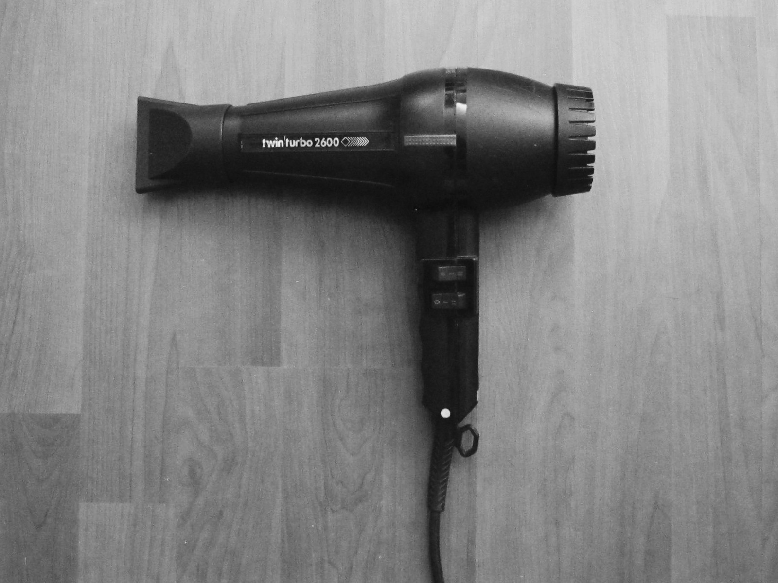 A black hair dryer on a wooden floor.