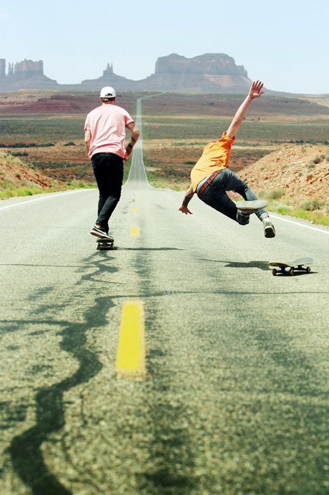 Two people skateboarding down a road.