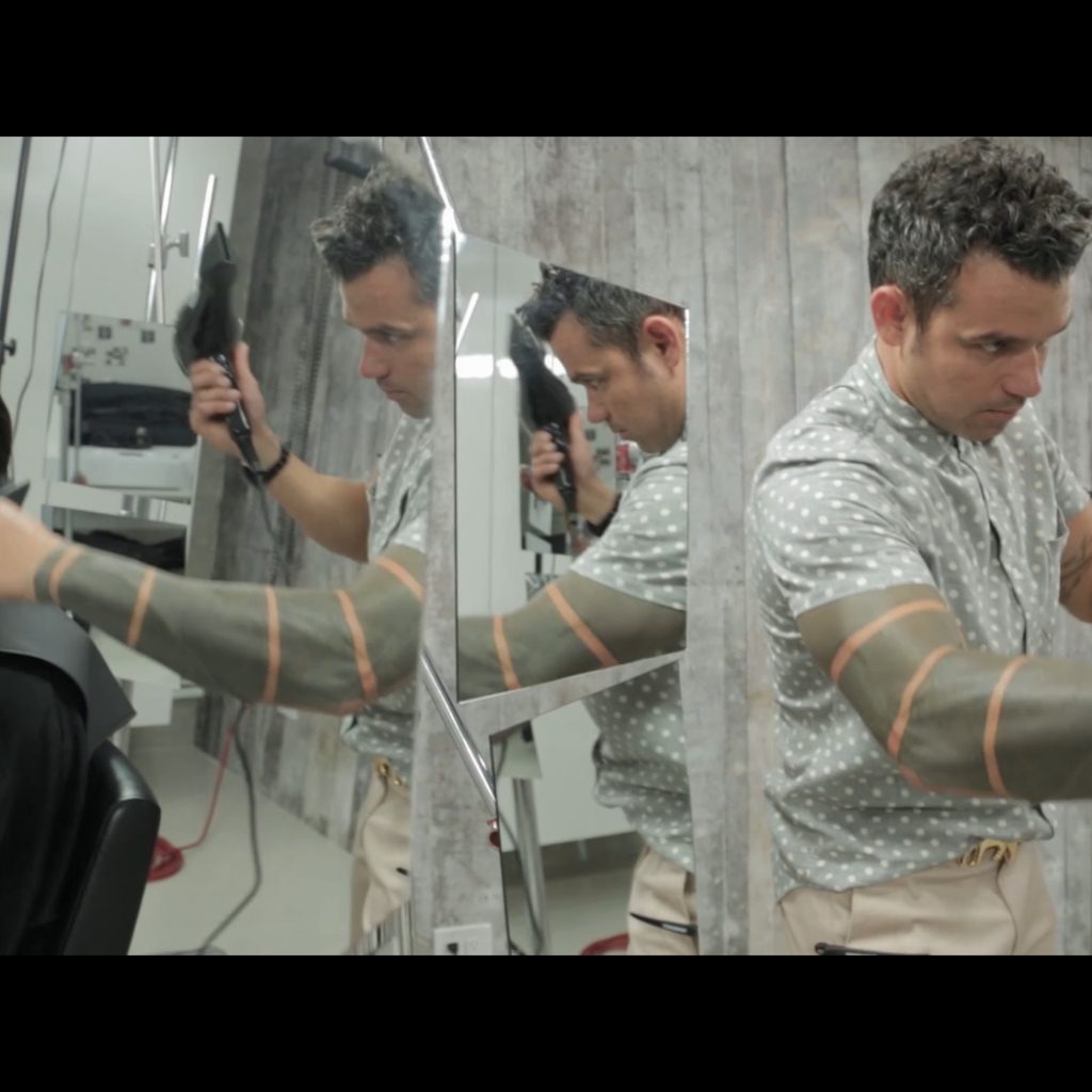 A man is getting his hair done in a mirror.