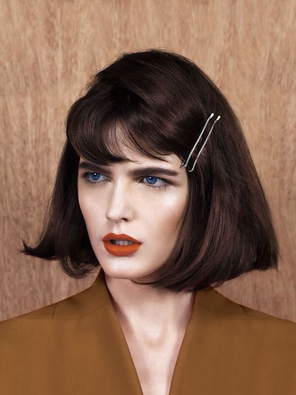 A woman with a bob haircut and orange lipstick.