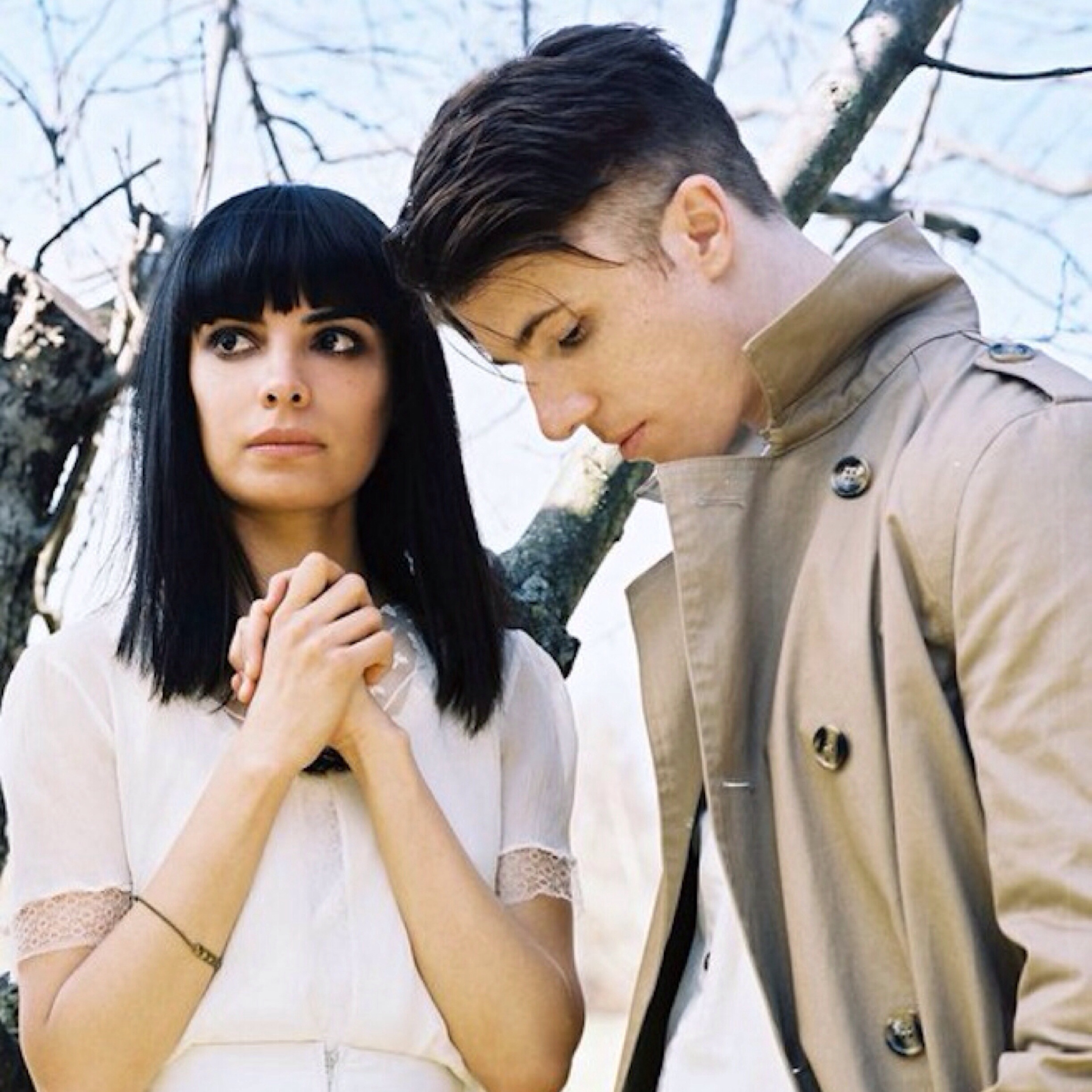 A man and woman standing next to a tree.