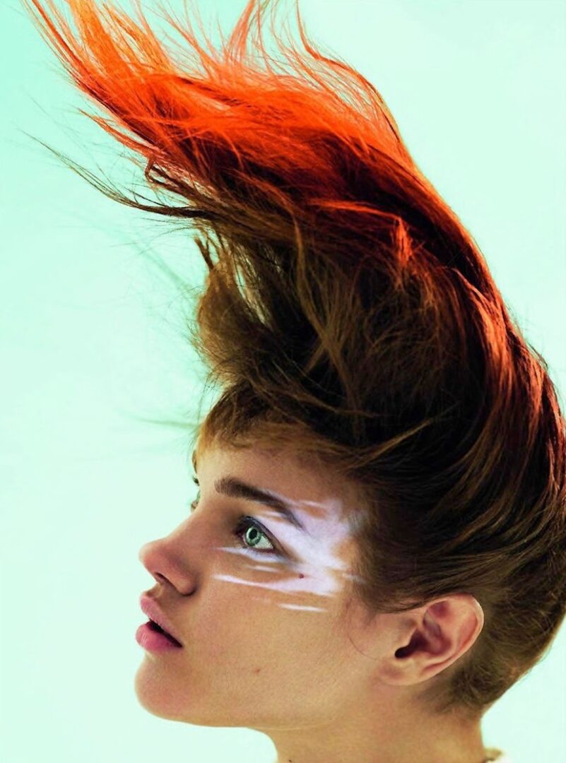 A woman with red hair and white paint on her face.