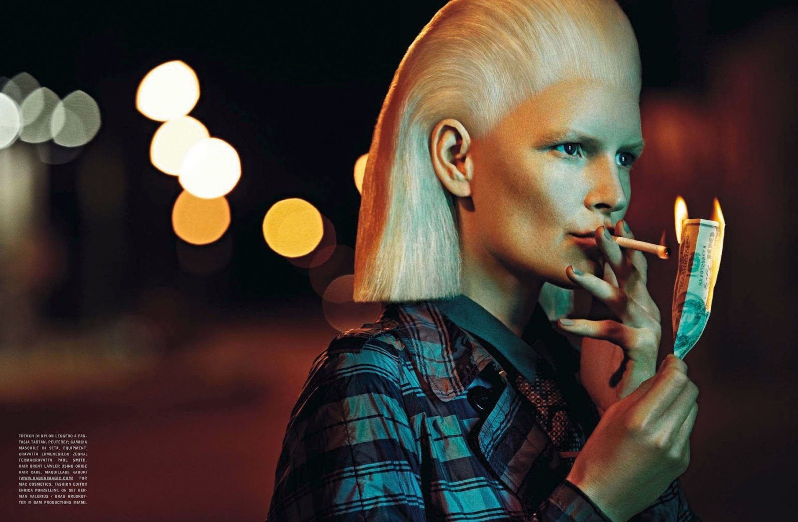 A woman with blonde hair smoking a cigarette at night.