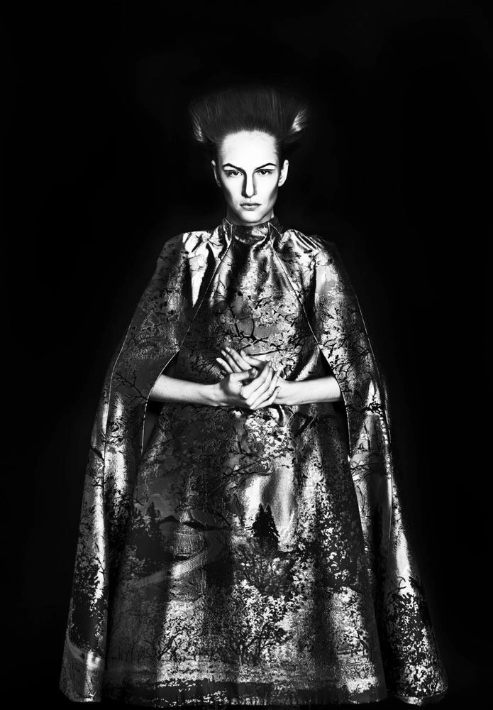 A black and white photo of a woman in a cape.