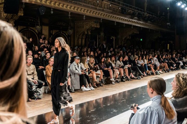 A woman is walking down the runway at a fashion show.