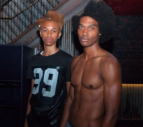 Two men with afro hair standing next to each other.