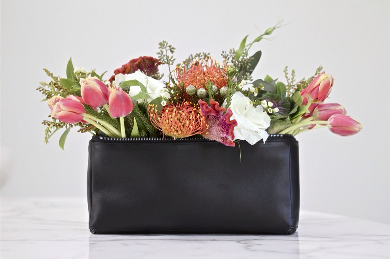 An arrangement of flowers in a black purse.