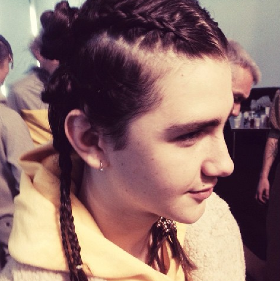 A girl wearing a yellow hoodie with braided hair.