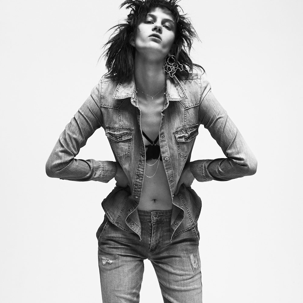 A woman posing in jeans and a denim jacket.