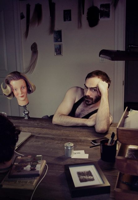 A man sitting at a desk with a mannequin head.