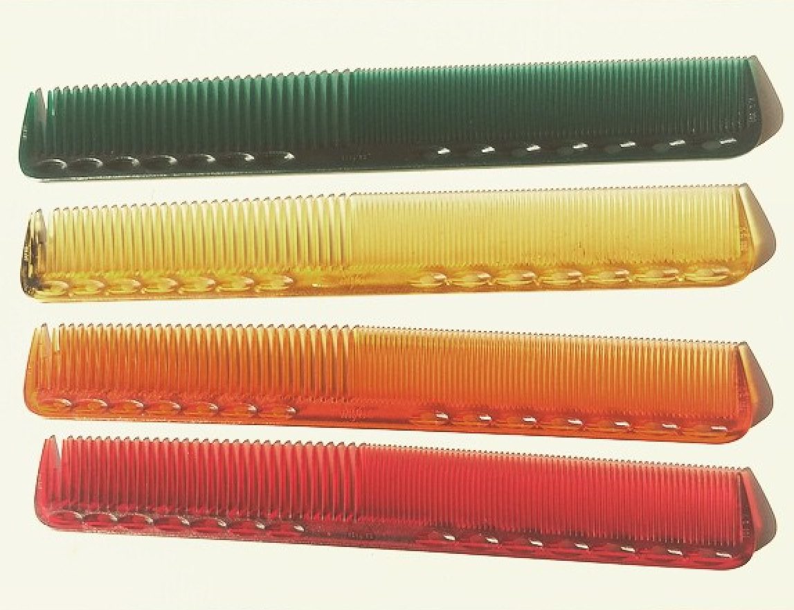 Four different colored combs on a white surface.