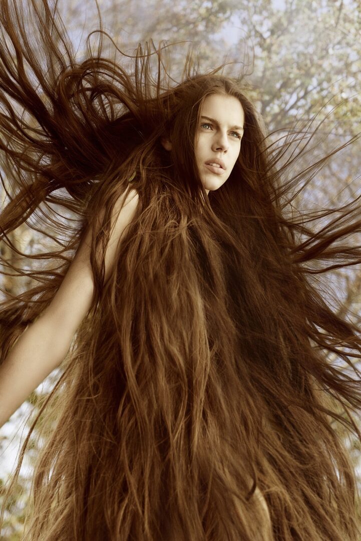 A woman with long hair in a forest.