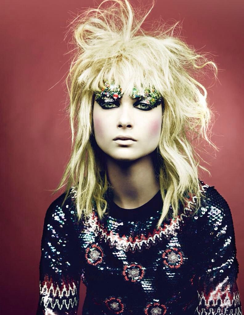 A woman with blond hair and sequins on her face.