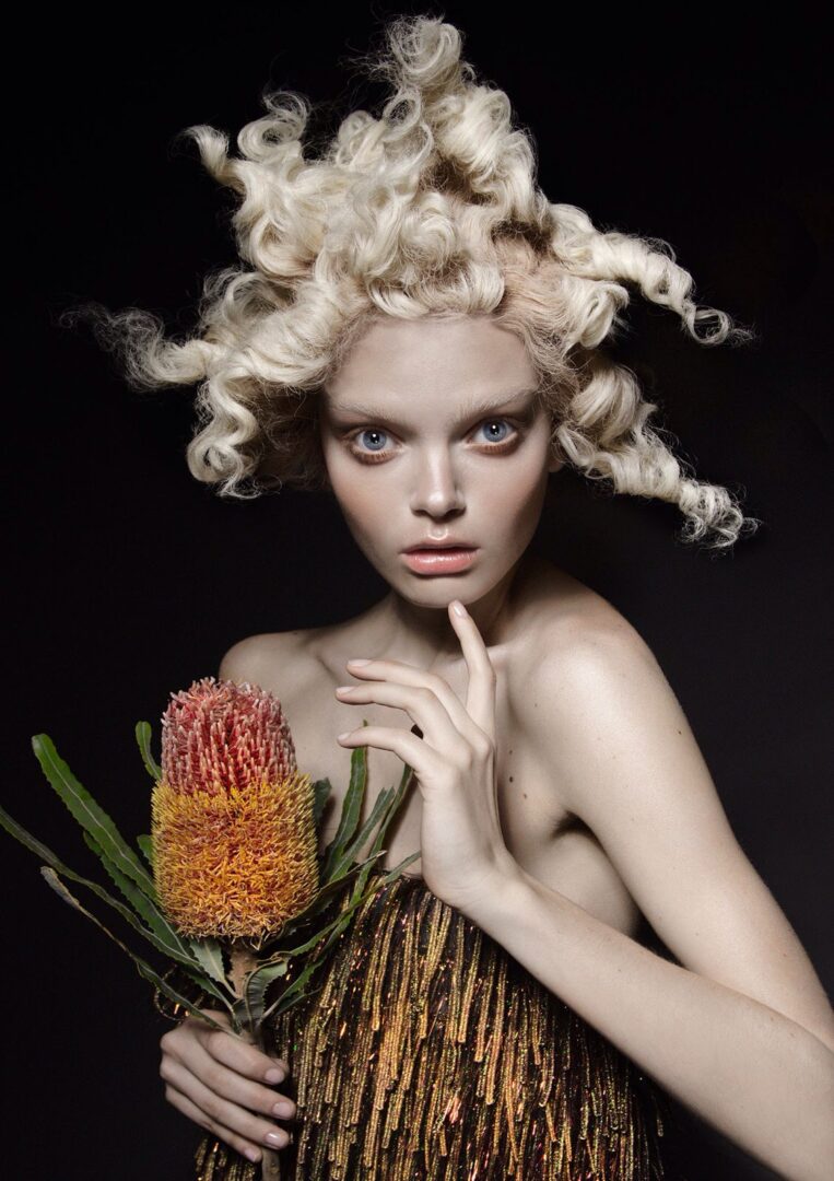 A woman with curly hair holding a flower.