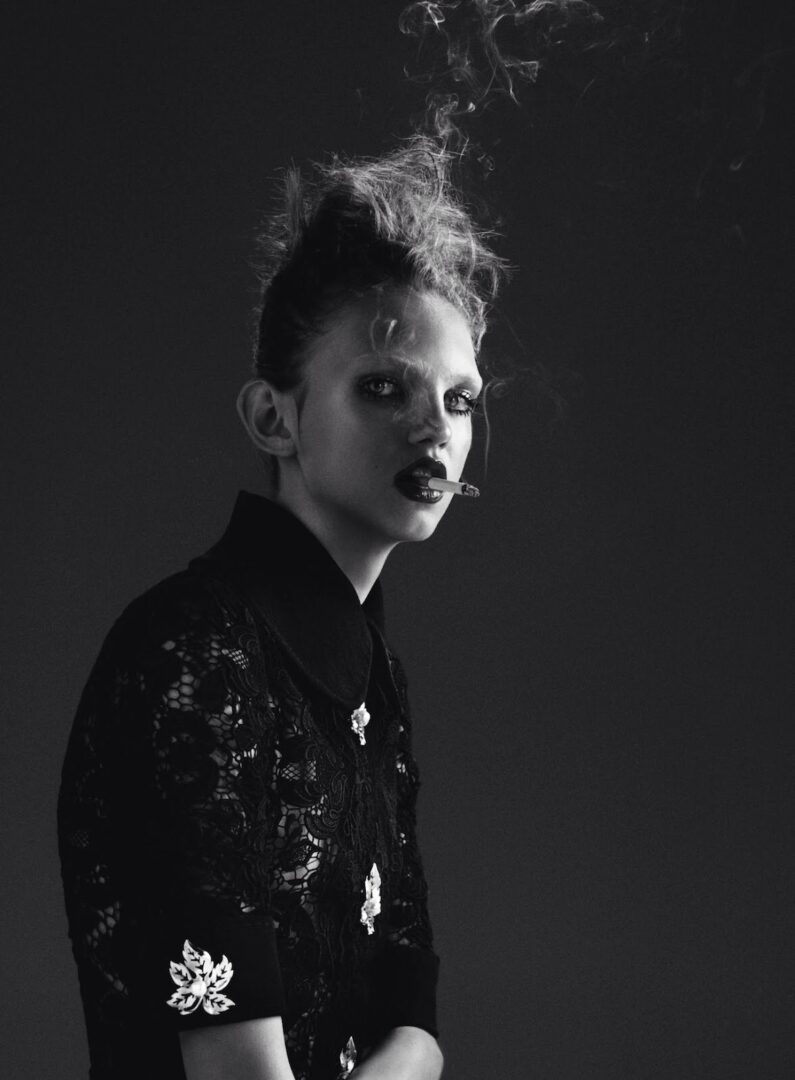 A black and white photo of a woman with smoke coming out of her mouth.