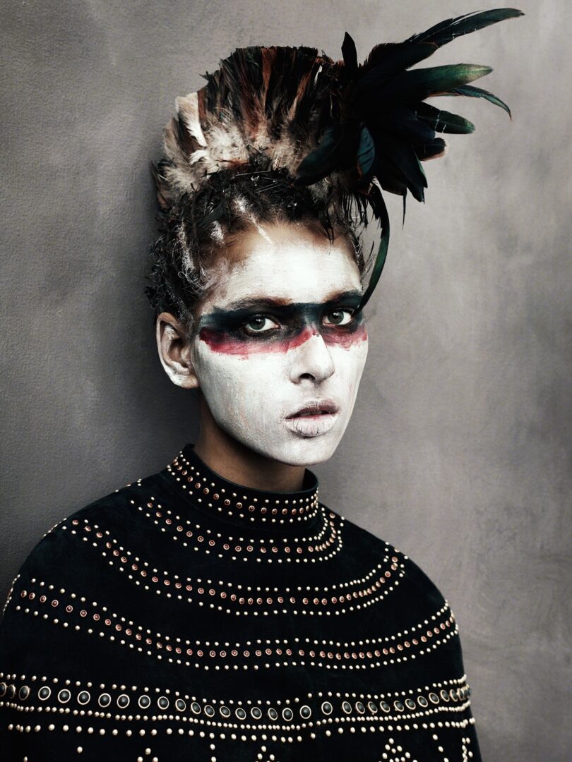 A woman with a feathered headdress is posing for a magazine.