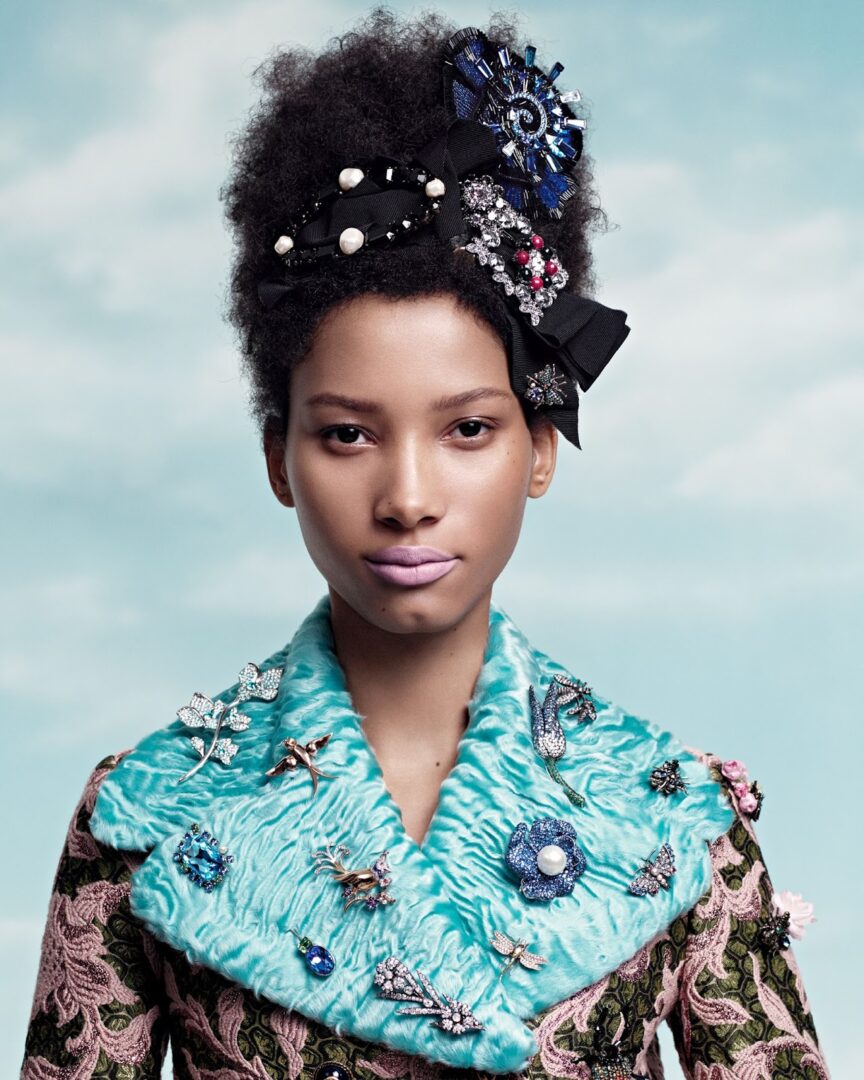 A black woman in a blue dress with a bow on her head.