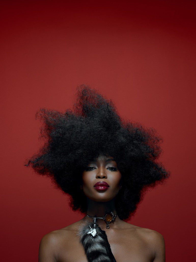 A black woman with an afro in front of a red background.